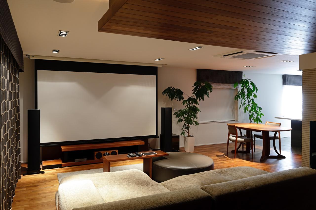 画像: Nさんのシアターでは、スクリーンと直視型テレビを併用した2ウェイスタイルを実践。午後の温かな日差しがシアター空間を満たす。壁紙やカーテンなどのインテリアコーディネートの実に巧みな設計が印象的だ