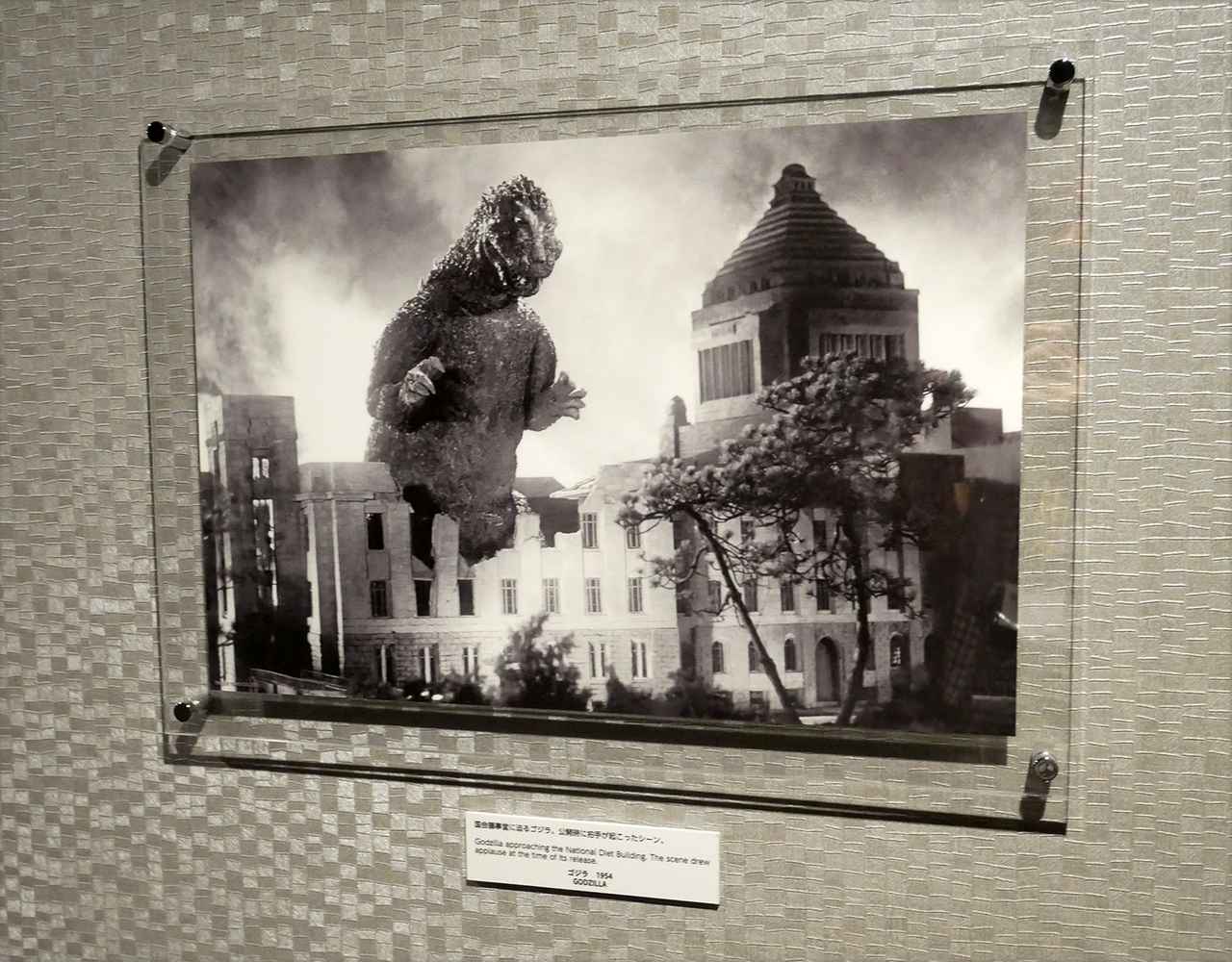 画像: 30Fの廊下に準備されたゴジラギャラリーには、歴代ゴジラ作品の名シーンのスチル写真が解説とともに展示されている