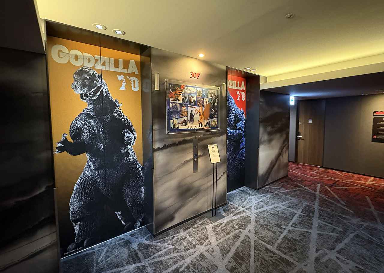 画像: 30Fのエレベーターホール。4基のエレベーターの扉にはそれぞれ異なるゴジラが描かれている。うち1台(『ゴジラ-1.0』)は、内部にもゴジラのペイントがあり