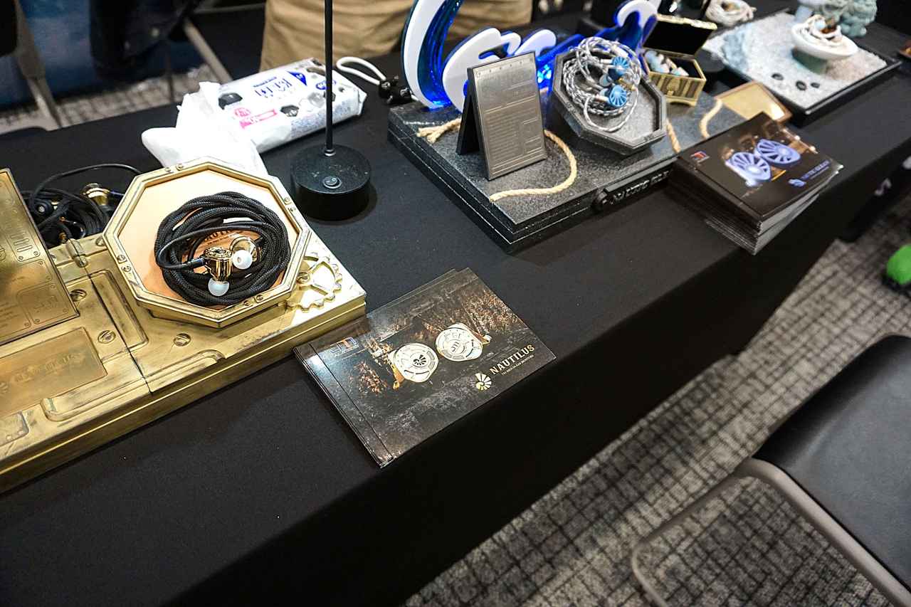 画像: ▲Jomo Audioでは、高級アクセサリーのような個性的デザインが特徴のイヤホン「NAUTILUS」(写真左)と「NAUTIG GLEAM」(写真右)が異彩を放っていた