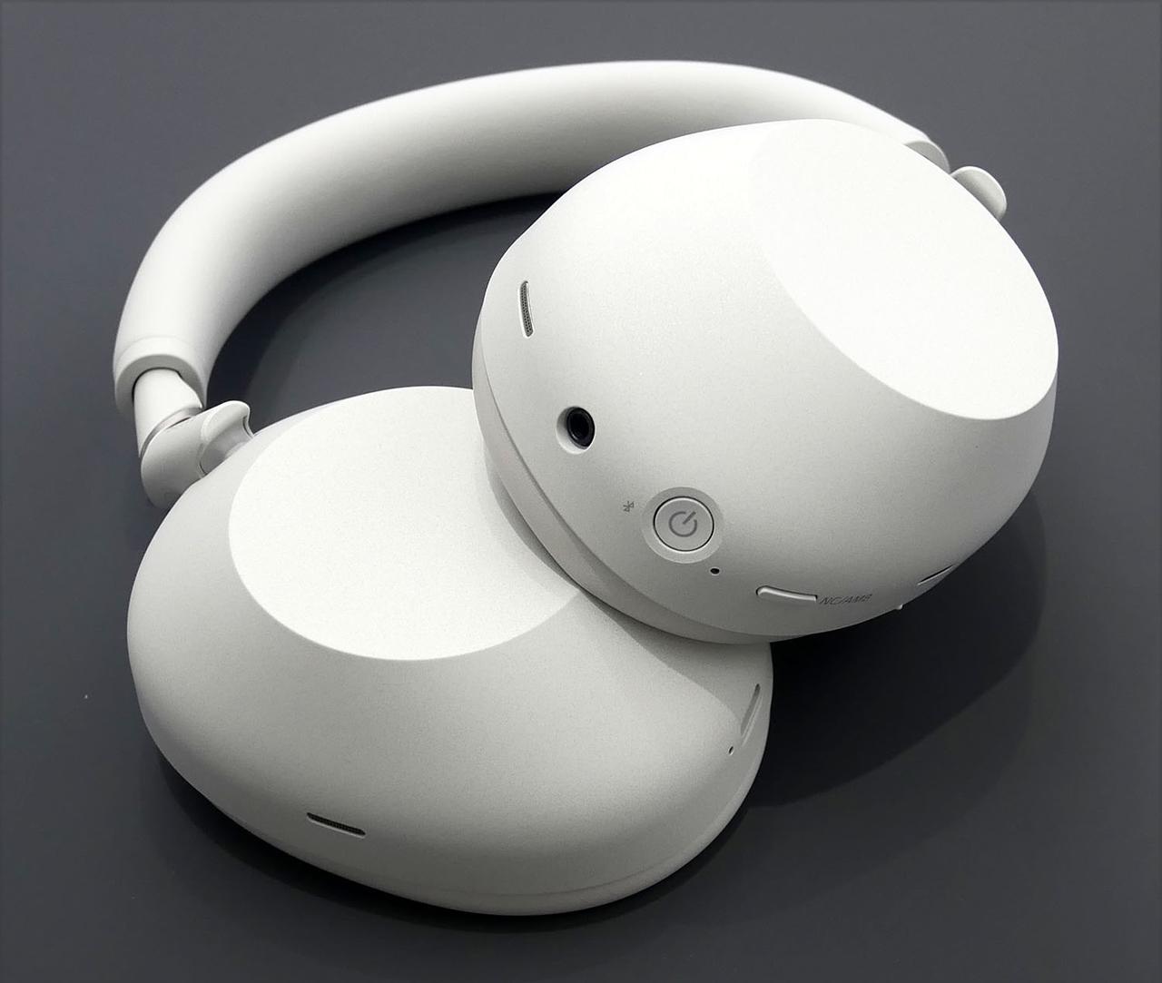 画像: 左ヘッドホン(写真の上側)には電源ボタンや3.5mmアナログ端子を備える。右側には充電用USB-Cコネクターもあり