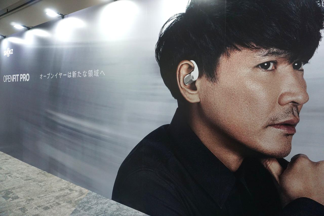 画像: 「OpenFit Pro」を装着した山口氏の広告パネル