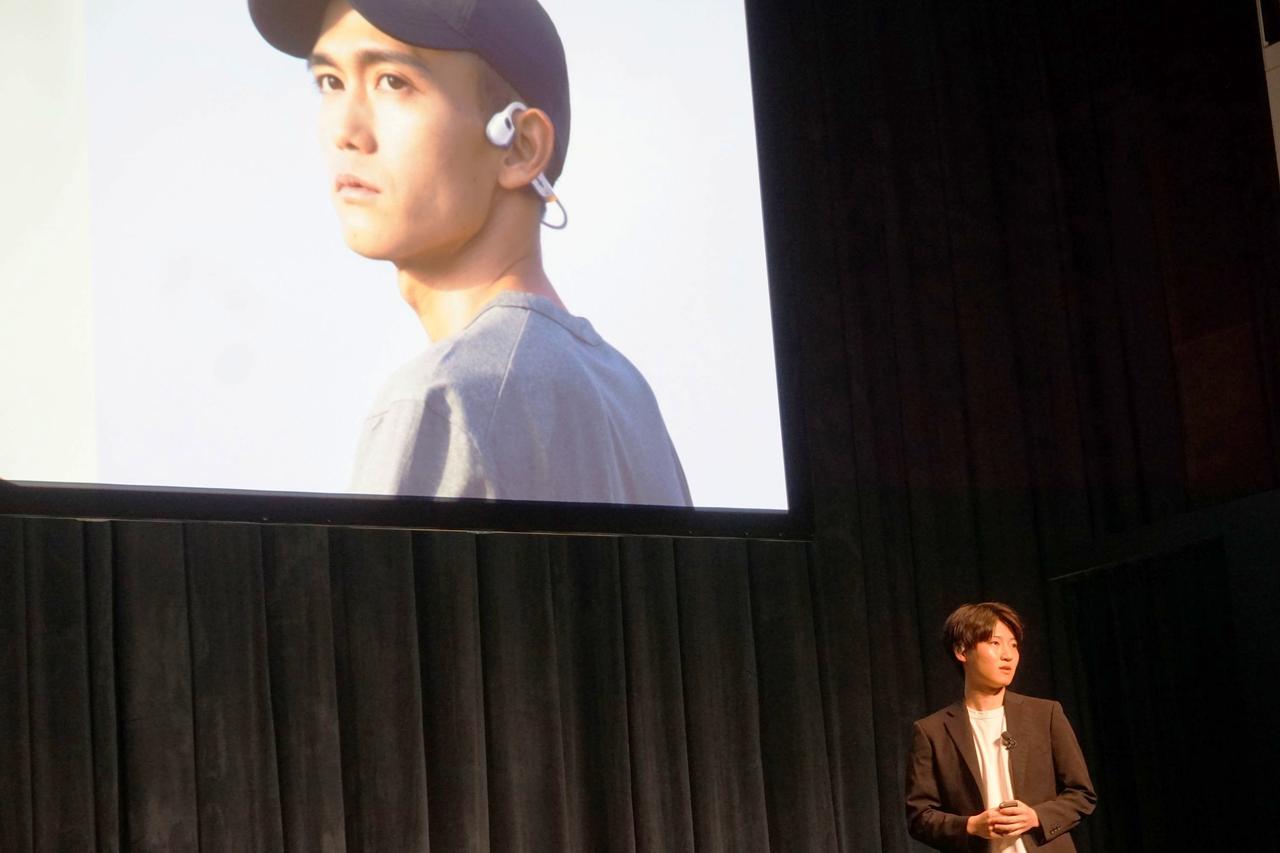 画像: Shokz Japan株式会社 CMO 冨田氏。スクリーンに映っているのは、2023年からShokzブランドアンバサダーを務めるプロランナーの大迫傑選手