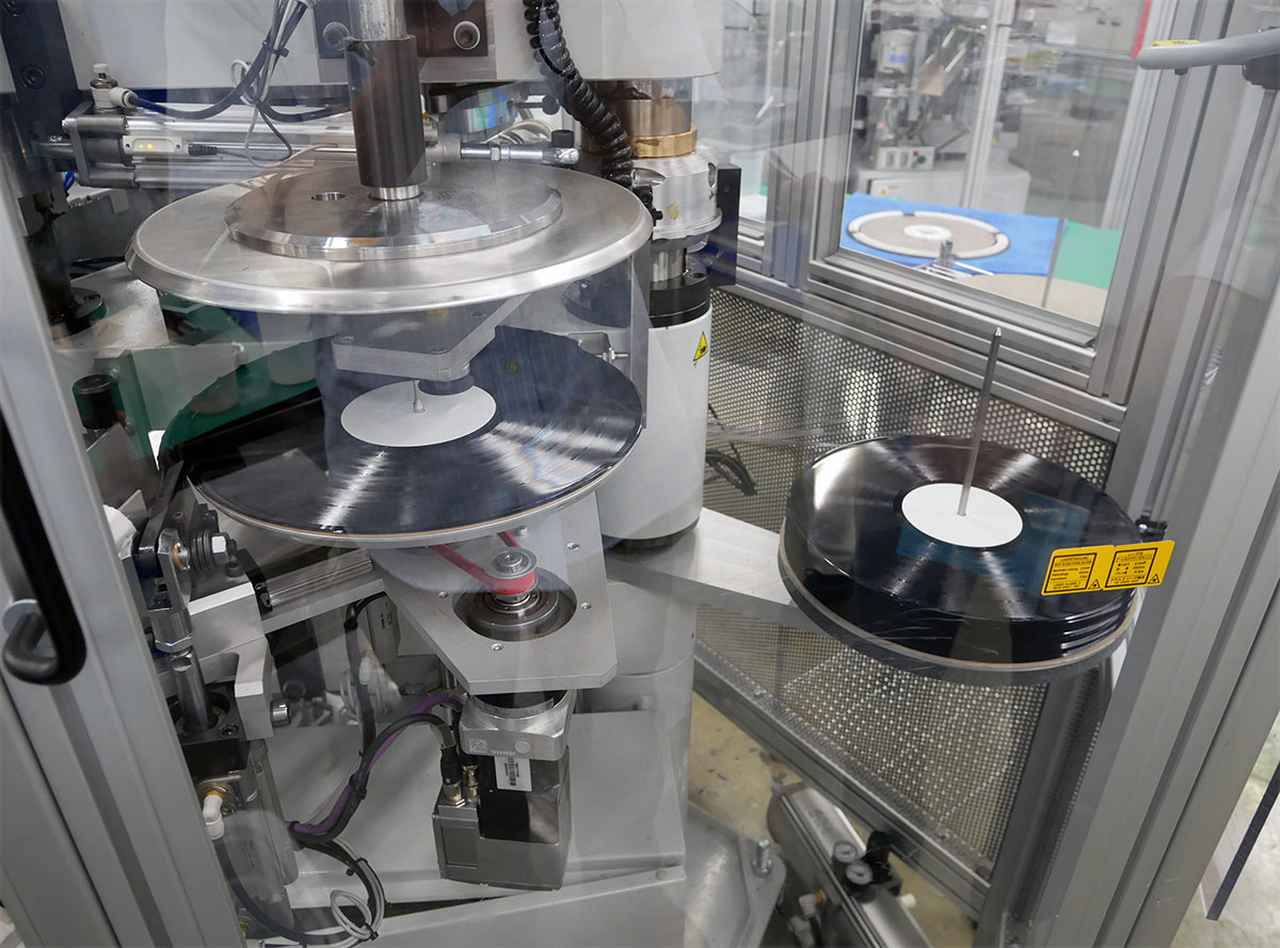 画像: 塩化ビニールは、130〜150度に熱した状態でプレスを行う（この温度も気候に応じて微調整するとか）。プレスマシンでは塩化ビニルの装填からプレス、不要な外縁部分のカットまで自動で行われる