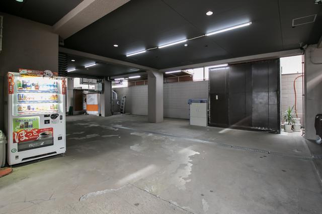 画像: 半地下の駐車場。奥に植木鉢が見えるあたり、黒っぽいカベのように見えるのが、棺用エレベーター側面