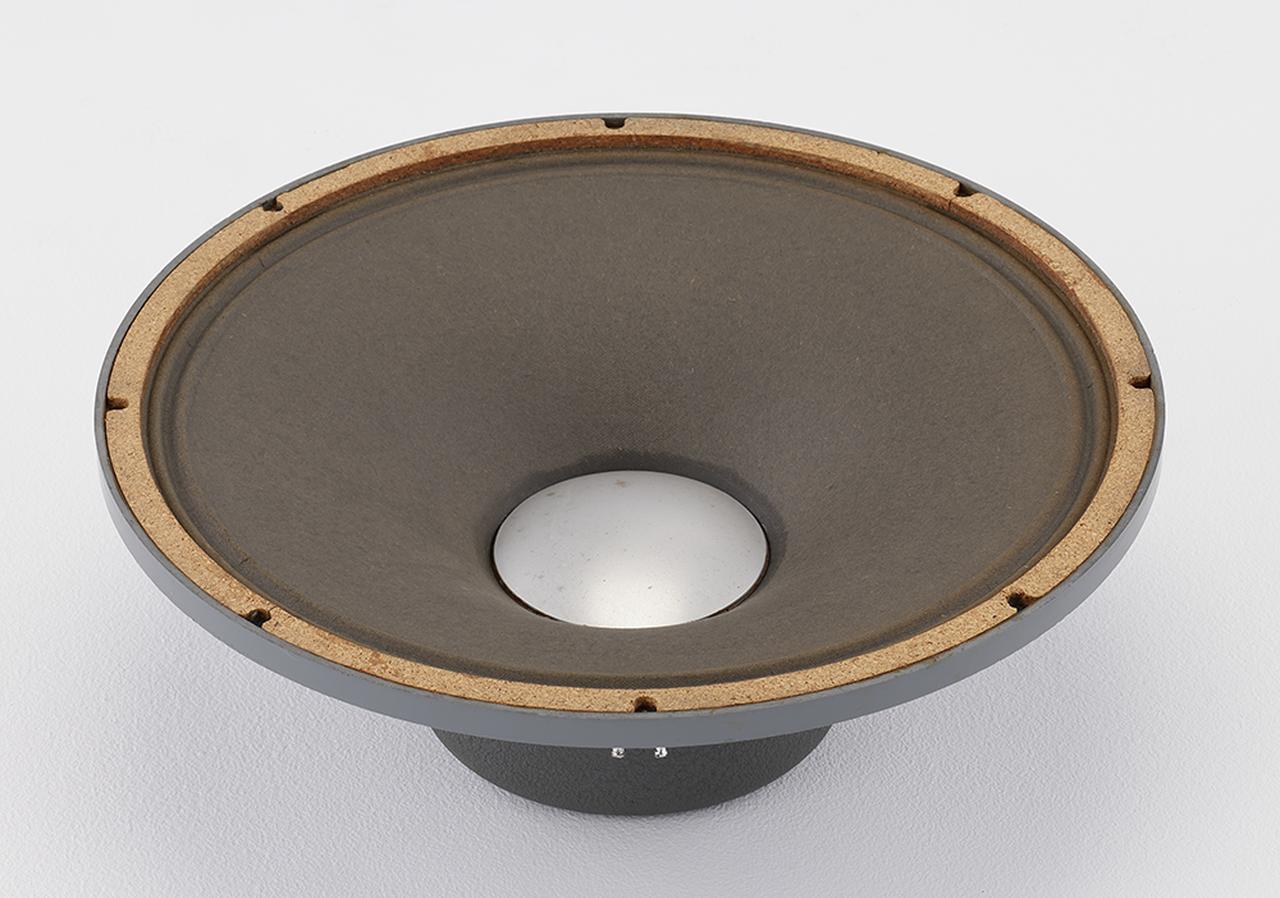 画像: D130はジェームズ.B.ランシング自身が設計し、1947年に登場した15インチフルレンジユニット。現在まで連綿と続くJBL製スピーカーユニットの源流にあたる。当時のアルテックや、前年に発売されたD101では3インチ径ボイスコイルを採用していたのに対し、D130では4インチ径ボイスコイルを採用している点が特徴。アルミのセンターキャップにより「エクステンデッド・レンジ」の名にふさわしい広帯域再生を可能にしている。初期型はバックカバー形状が平らなフラットバック仕様で、1953年頃に鋳鉄製のエッジが丸い形状に変わり、高域のレスポンスが向上した。その後も仕様変更を重ねながら、1980年頃まで販売されていたロングセラーモデルである。