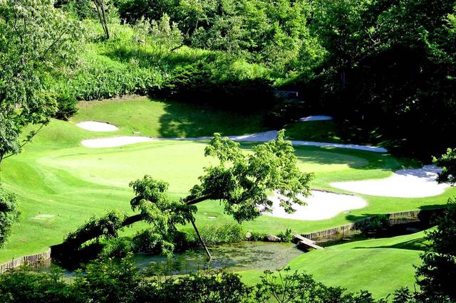 画像: 大きな打ち下ろしの15番パー3(168Y)。グリーン手前に小川、前後をバンカーが囲む。小さめ番手で距離を合わせよう
