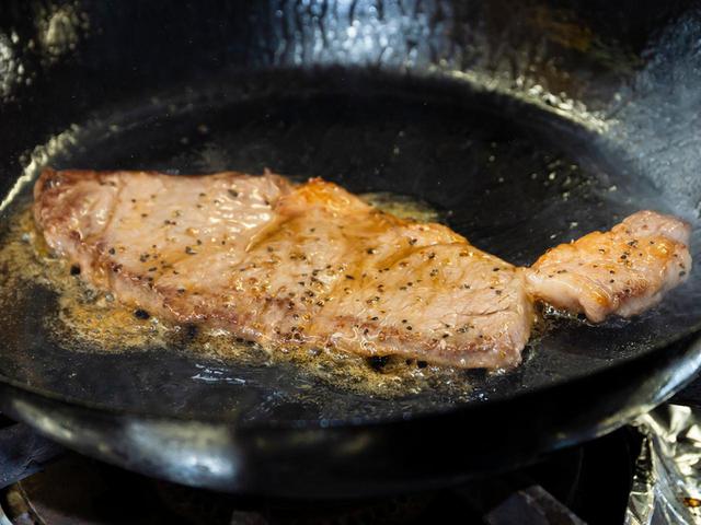画像: 1枚ずつ強火でバターを回しかけながら焼き、ミディアムレアに仕上げる。ステーキはたっぷり2枚分