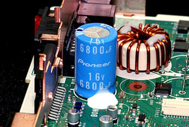 画像: オーディオ電源回路には、フルカスタムアルミ電解コンデンサーや高音質トロイダルコイルを採用。コンデンサーは、電解液の調合はもちろん、制振性能を高めた専用スリーブ(表面の青いカバー)までカスタマイズしている。コイルは線径を太く、コアの高さを上げるなど低抵抗化を実施している。これにより低音のグリップ感や制動力がアップしているという。
