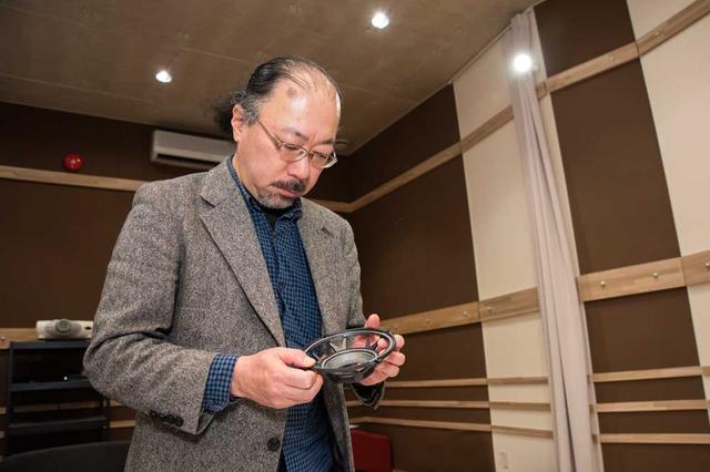 画像: ウーファーユニットのアルミダイキャストバスケットフレームを手にする筆者。フレームはV字型の支柱を6本備えたデザインで、素材および構造によって不要な振動を抑える設計となっている。