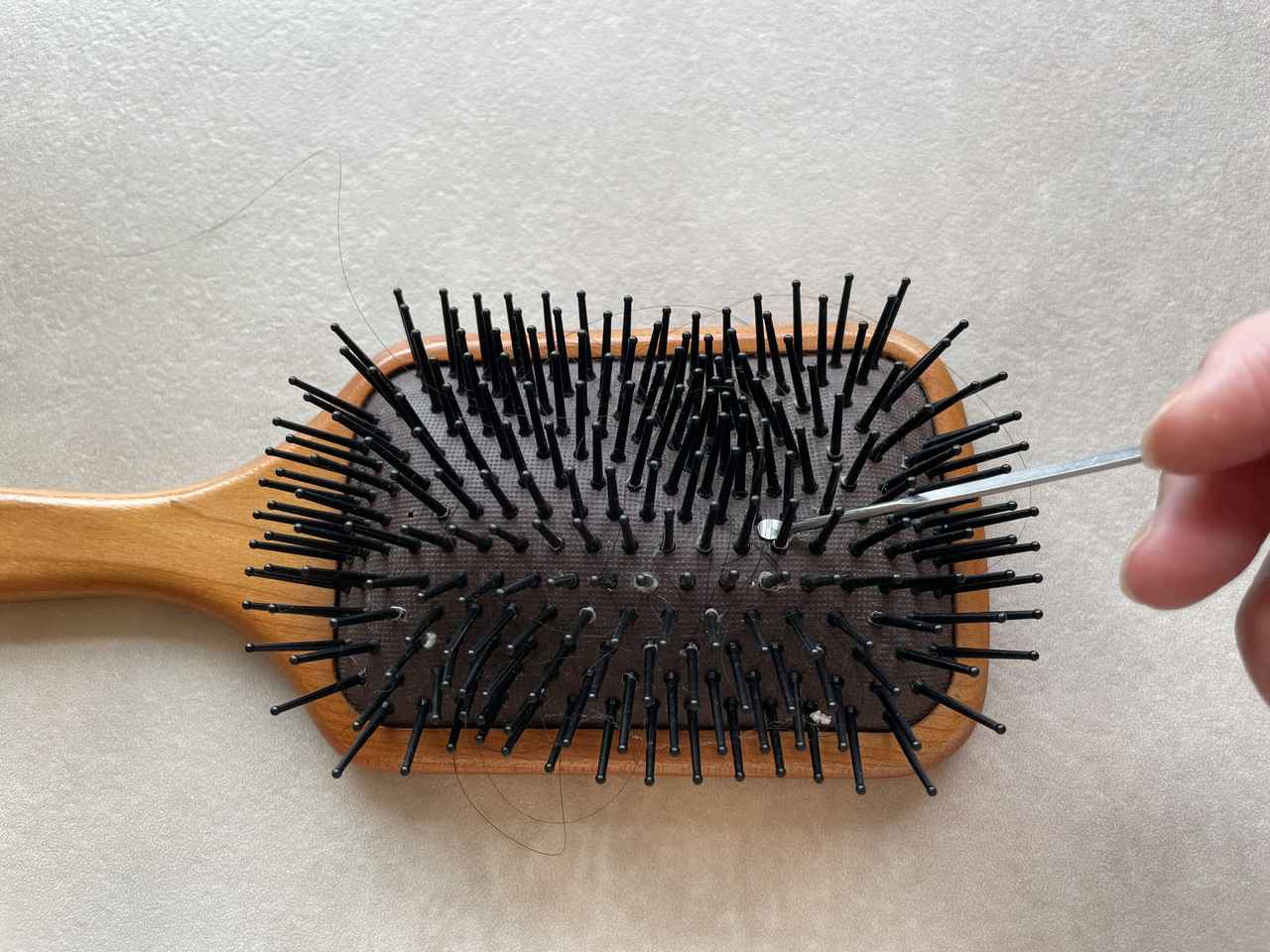 画像: 耳かきでヘアブラシの汚れを取っていた