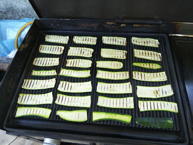画像: BBQ用の鉄板上に5㎜程度にスライスしたズッキーニを並べる (筆者撮影)
