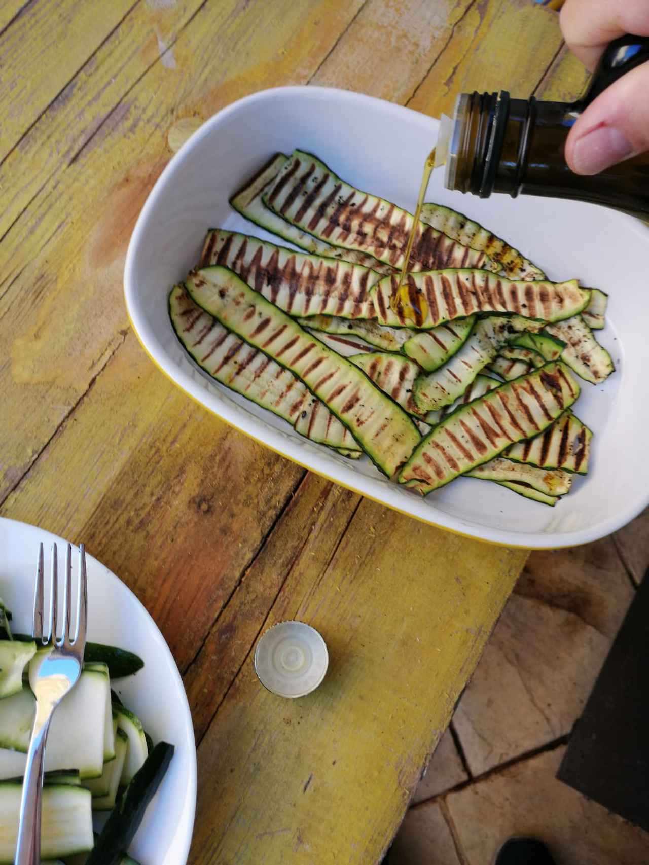 画像: 焼いて塩を振ったズッキーニにオリーブオイルをかける (筆者撮影)