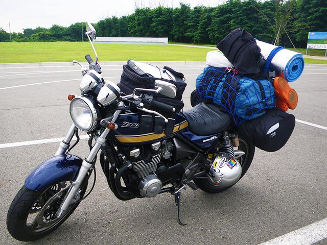 画像: 銀マットを2枚重ねて巻きベルトとカラビナを組み合わせて荷物に固定(ツーリングキャンプでの一コマ) (筆者撮影)