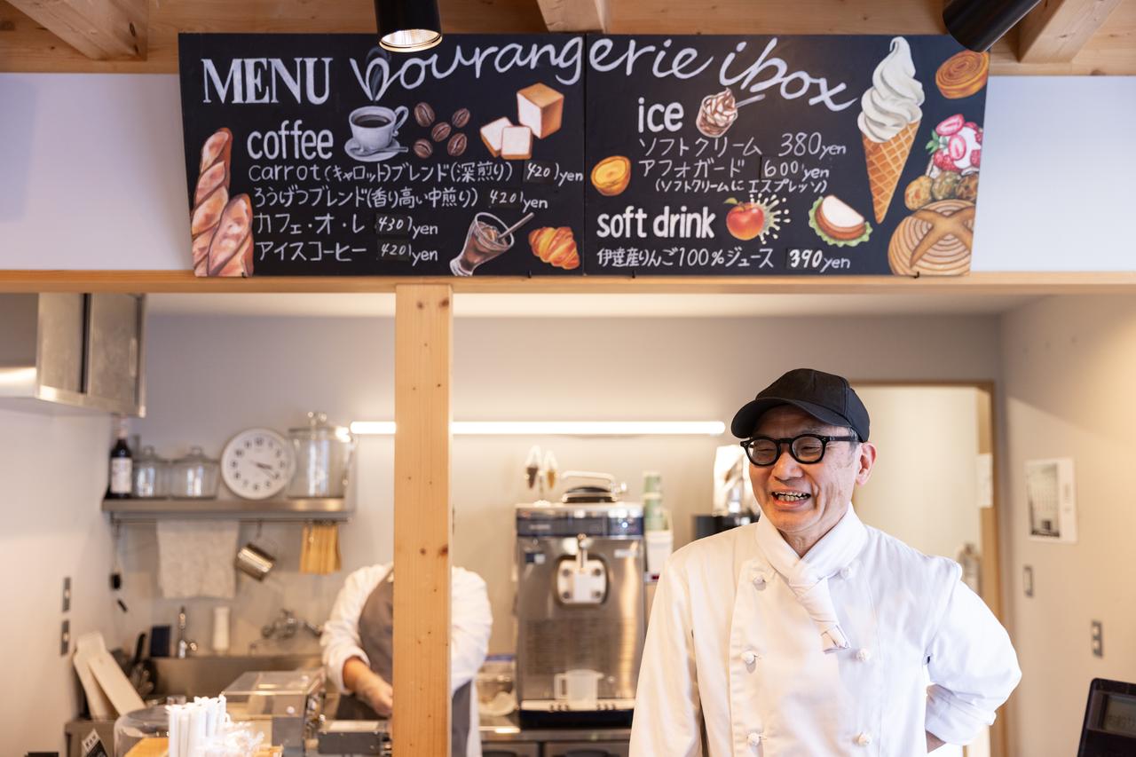 画像: 店長の武田さん。壁に掲げられたメニュー看板のイラストは、利用者さんが描いたもの