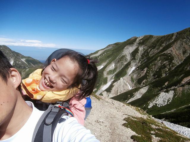 画像: 当時小学生だった娘さんを背負って山を登っている地引さん。お父さんの背中でとても楽しそうに笑っている