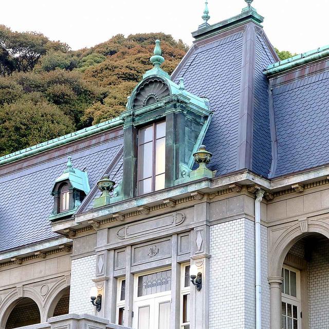 画像: 屋根は丸くうろこのように張られたスレート、銅板の出窓、外壁にはタイルが使われています。