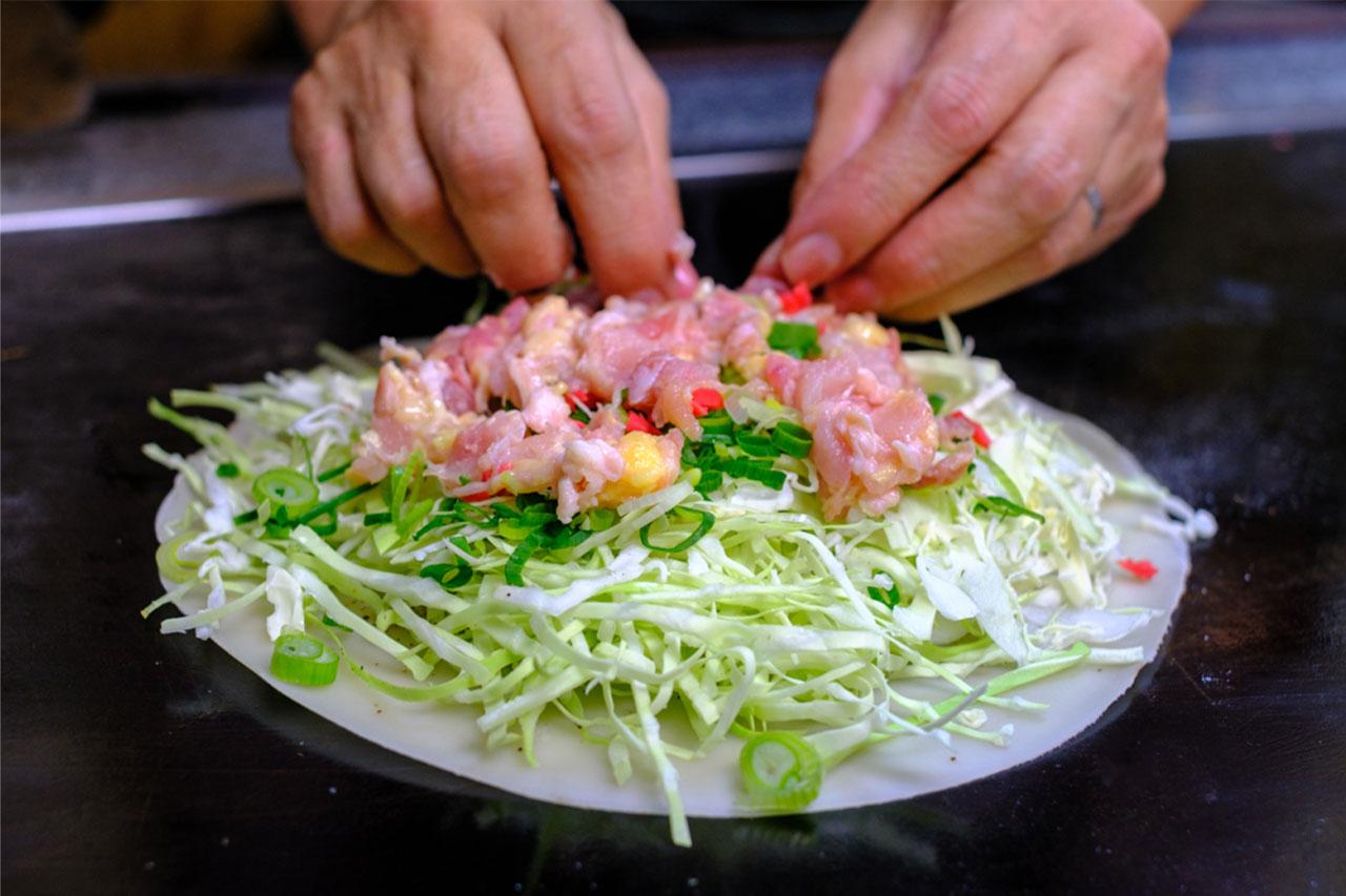 画像: 「洋食焼」はまずクレープをつくる。たっぷりと鶏肉を乗せた後、紅ショウガ、牛脂ミンチを乗せていく