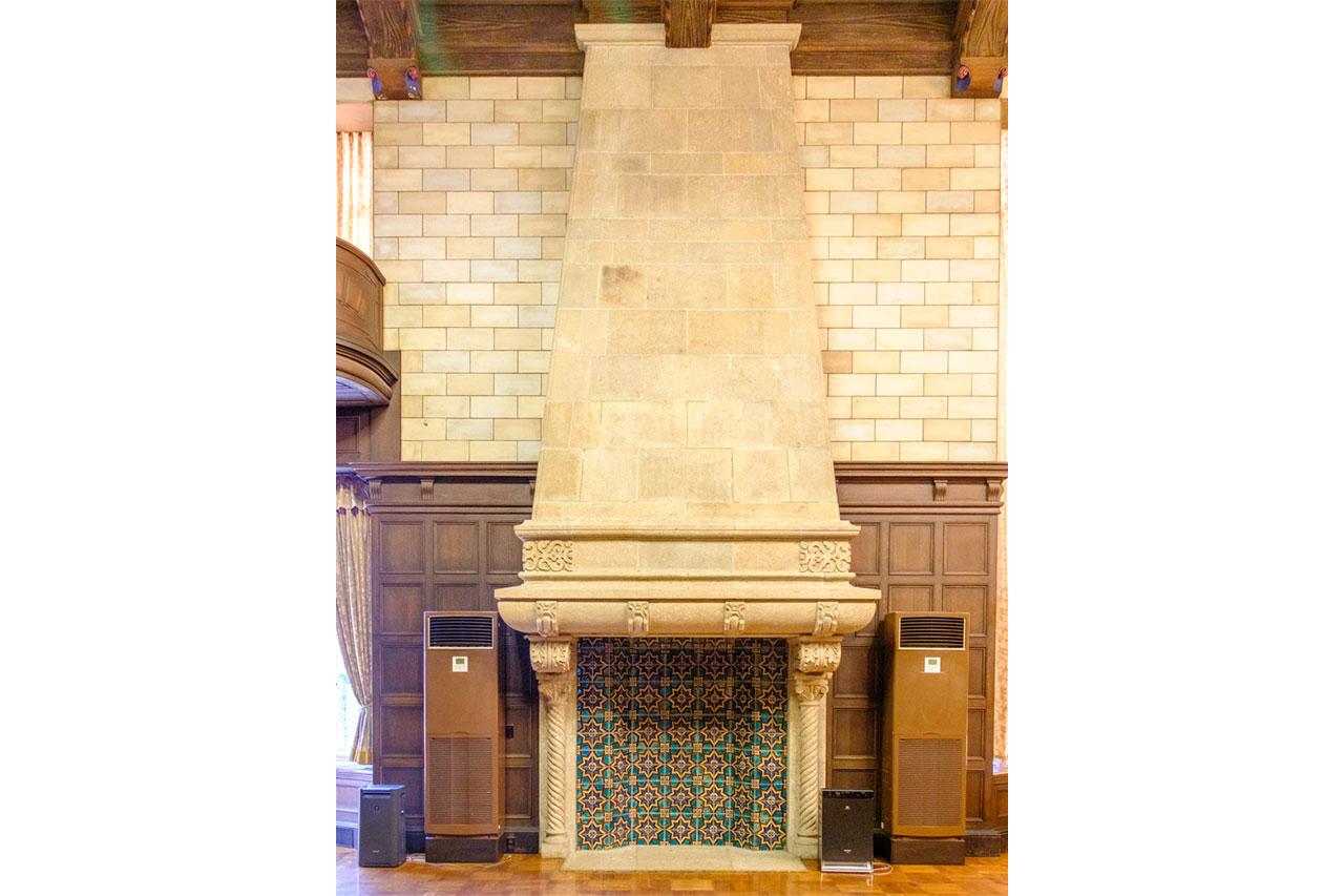 画像: 背の高い装飾暖炉が象徴的。深いグリーンのタイルがはまる