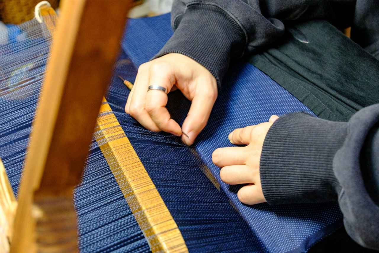 画像: じっくり丁寧に紡がれる色と柄。職人の集中力と時間が織り込まれる