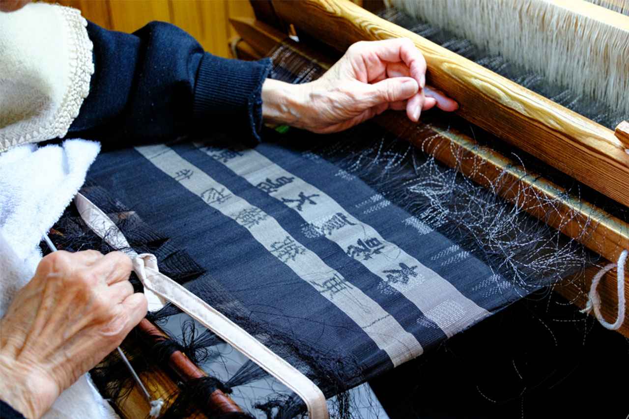 画像: 緻密な柄を表現するため、職人は針で微細な絵柄の調整を行う。仕上げに至るまで、職人の繊細な手仕事が途切れることはない