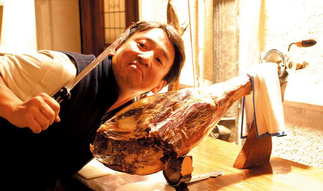 画像: 白豚の後ろ脚のみから作られるスペイン産の生ハム「ハモン・セラーノ」。骨と蹄が付いた美味なる塊を前に、「食うぞ」とおどけてみせる。