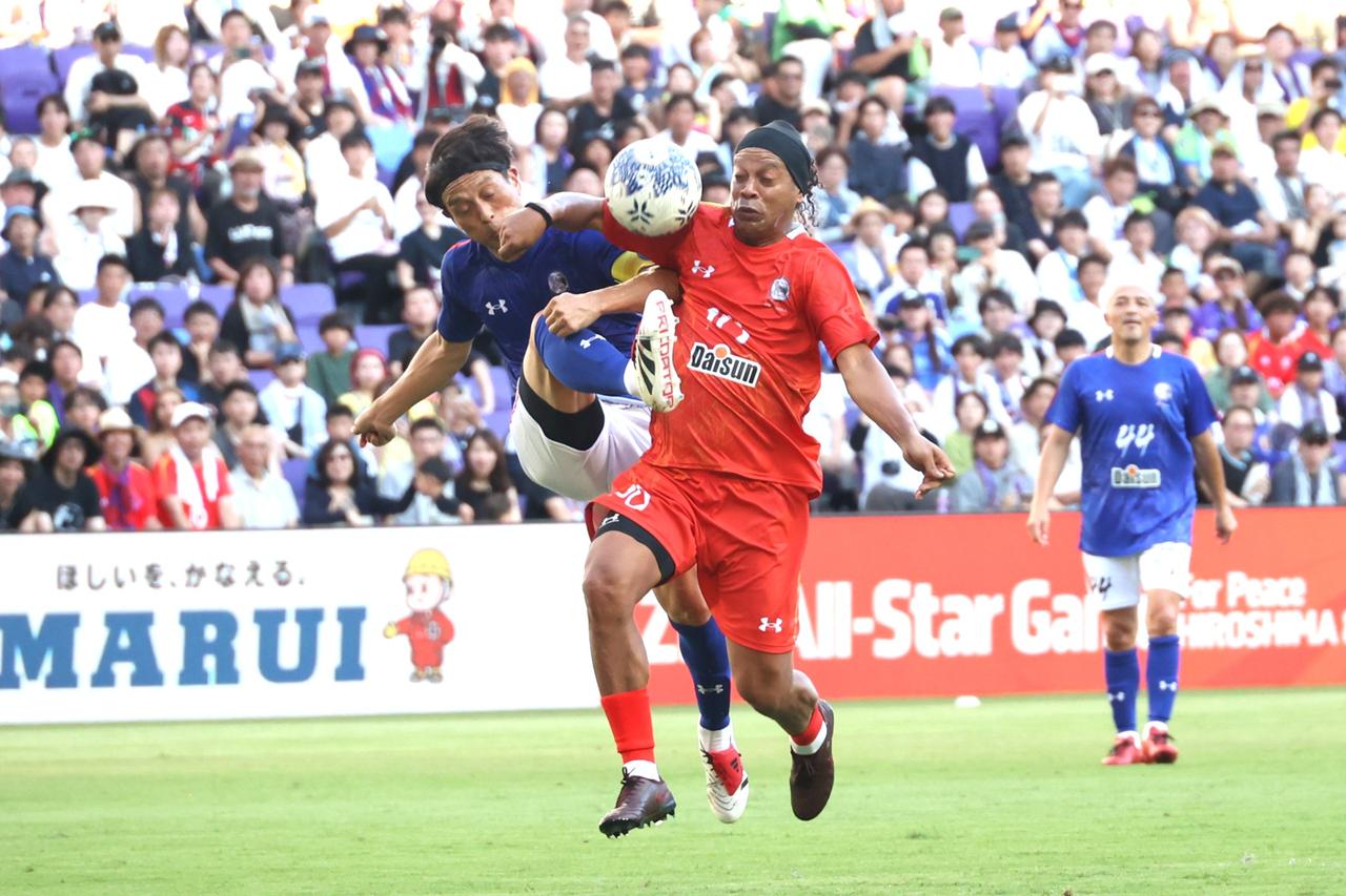 画像 : 2番目の画像 - 【写真】キャプテンマークを巻いてフル出場した宮本会長。ロナウジーニョと激しく競り合い、セットプレーから得点も狙った（写真◎石倉利英） - サッカーマガジンWEB