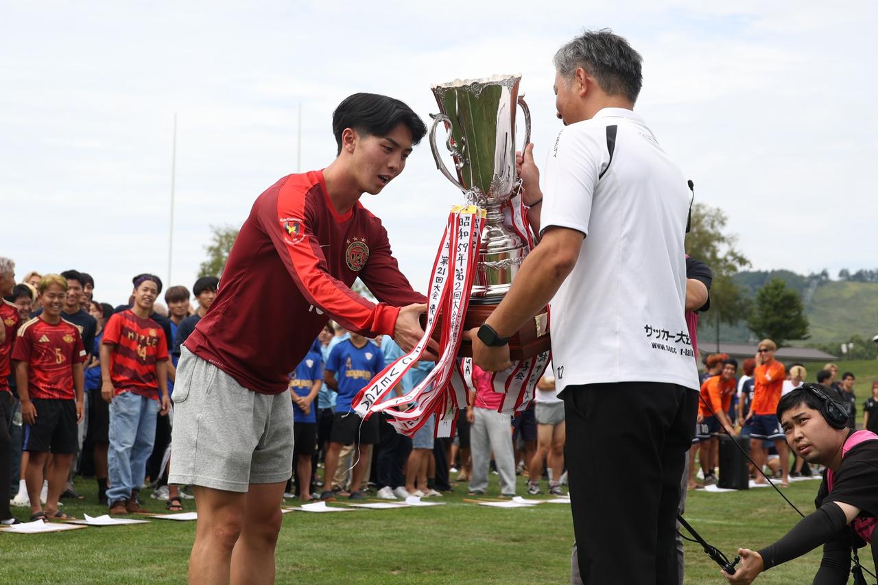 画像: 昨年優勝の慶應義塾大理工学部体育会サッカー部A・佐野大知が優勝カップを返還