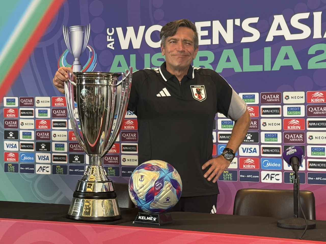 画像: 前日会見で優勝トロフィーとポーズを取るニールセン監督