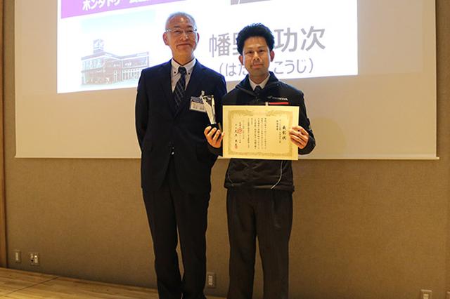 画像: サービス部門(HMSE3級)表彰。足立会長(左)と最優秀賞の幡野功次さん