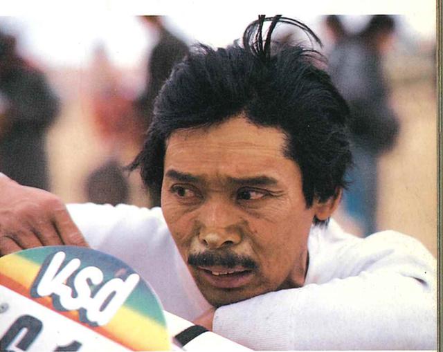 画像: 1985年、パリダカへ参戦時。1月8日、ニジェールにおいて撮影。「砂が顔のシワに沿ってたまり、ひどい顔になった」という浅賀さん(写真と文・出典:永岡書店昭和60年発行「JAPS WANT DESERT」より)