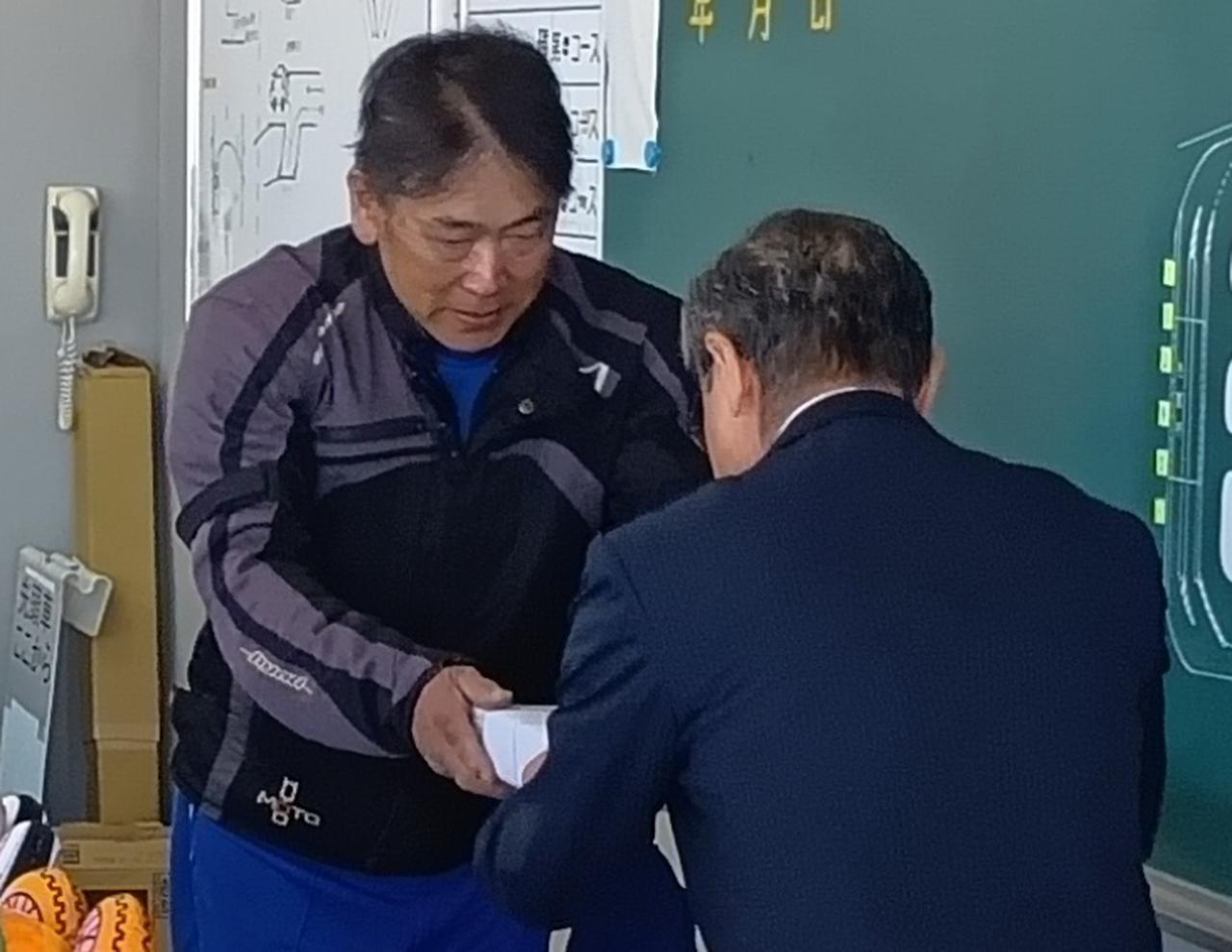 画像: 宮城での表彰伝達式。県安協の鈴木一浩事務局長（写真手前）から表彰盾を手渡される高橋特指