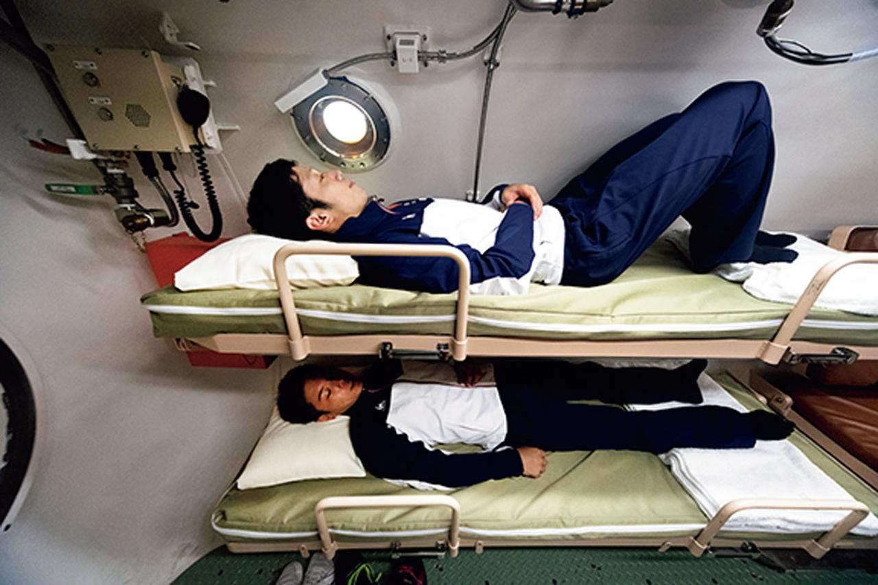 画像: ベッドは2段式で3組。枕元には読書用のランプが設置されている。ベッドは普段は上段が畳まれていて、長イスのようになっている