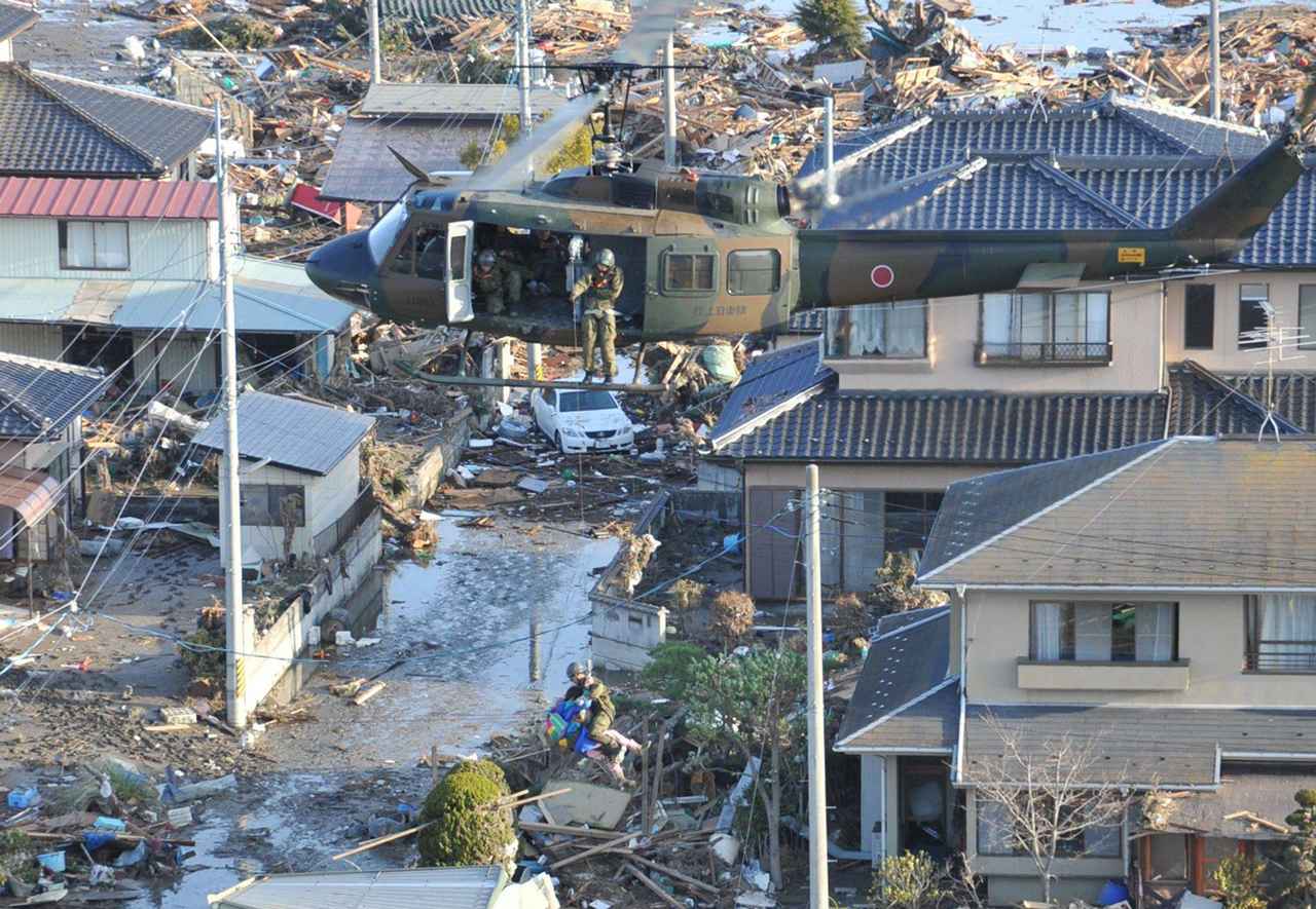 画像: 2011年3月の東日本大震災で救助活動を行う陸自ヘリ、電線や電柱を巧みにかわし、ギリギリまで地上に接近し隊員を降ろしていく