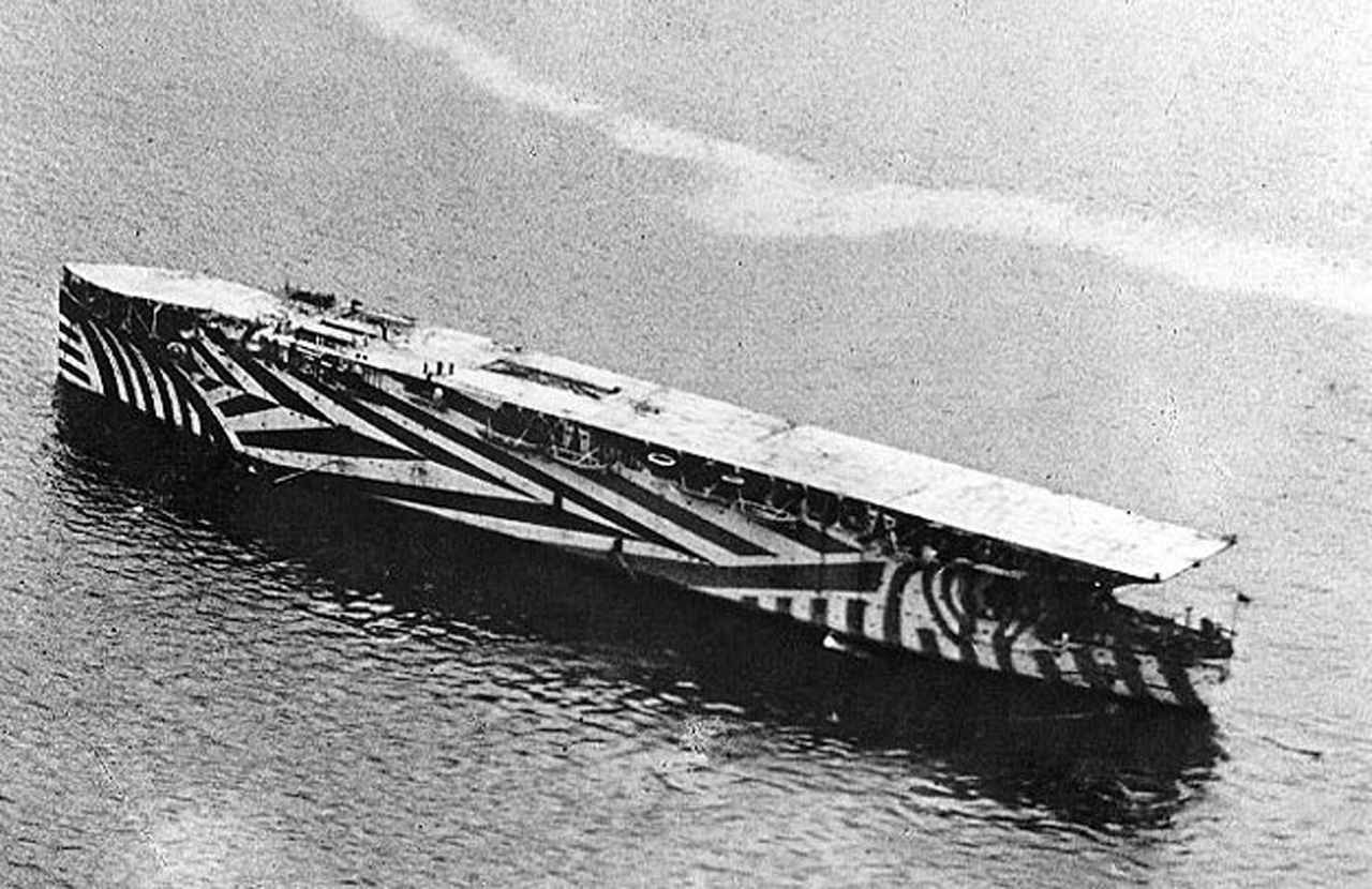 画像: 複雑な幾何学模様で塗装された「ダズル迷彩」を施されたイギリス空母『アーガス』。肉眼で見たときに、針路や速度がわかりにくくなる効果を狙い施されている 出典/U.S. Navy