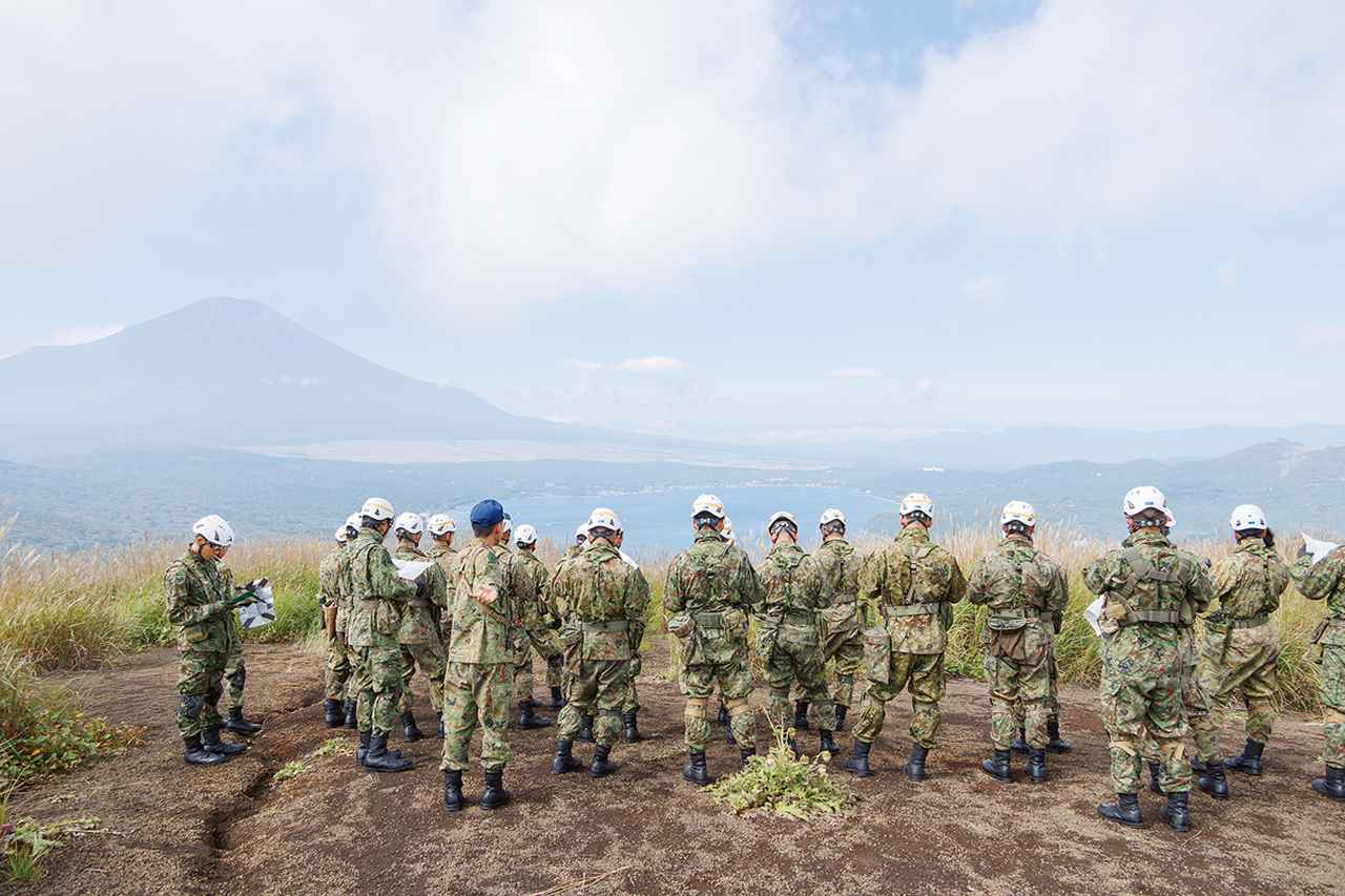画像: 地図とコンパスを手に、丘の上から自己位置の標定に使えそうな地物を探す幹部レンジャー学生たち