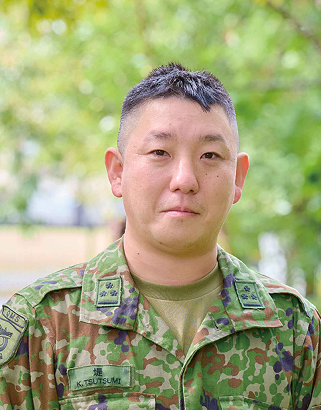 画像: 堤1尉は、山菜や野草になじみのない若い隊員に、食べられる野草と、その調理方法を教えている