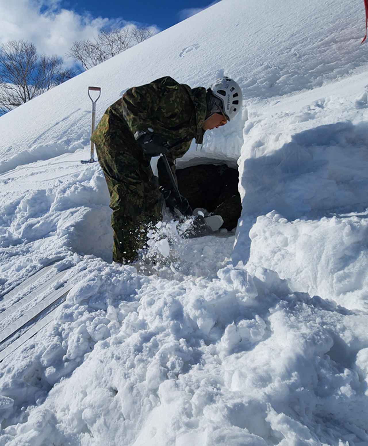 画像: シャベルを使って雪洞を掘る隊員。出入り口は居住スペースより下に作る