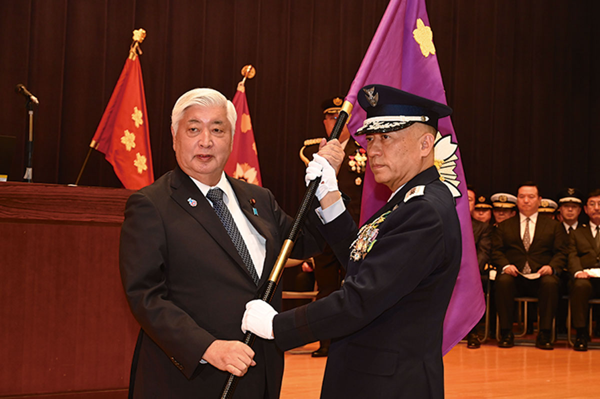 画像: 発足式で、部隊旗を受け取る初代司令官の南雲空将。同日に部隊のロゴマークも発表された 写真提供/防衛省