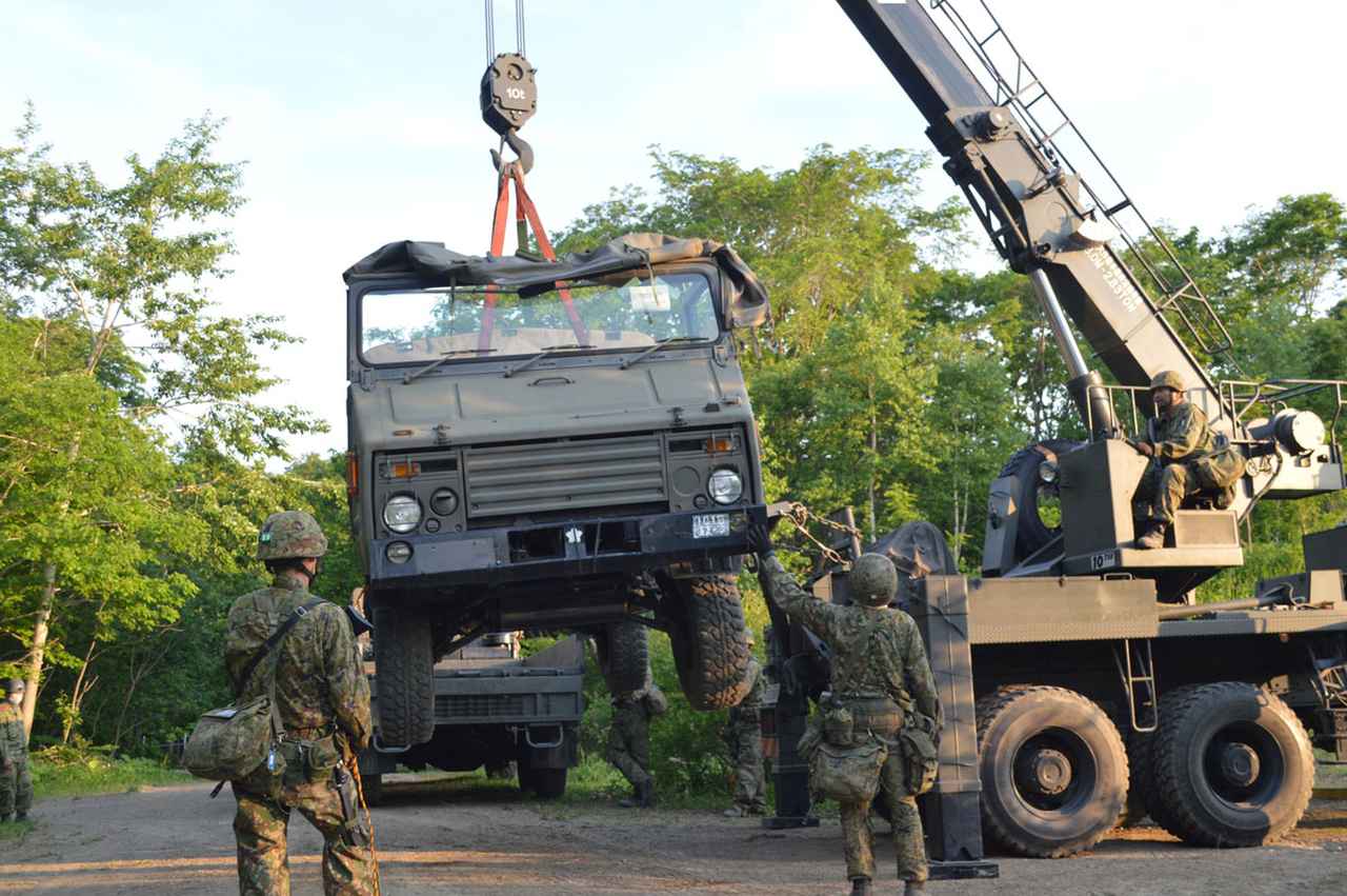 画像: 重機で車両をつり上げる第101施設直接支援大隊の隊員ら。車両の整備も担当する。有事の際は、現地で応急処置として整備を行うこともある