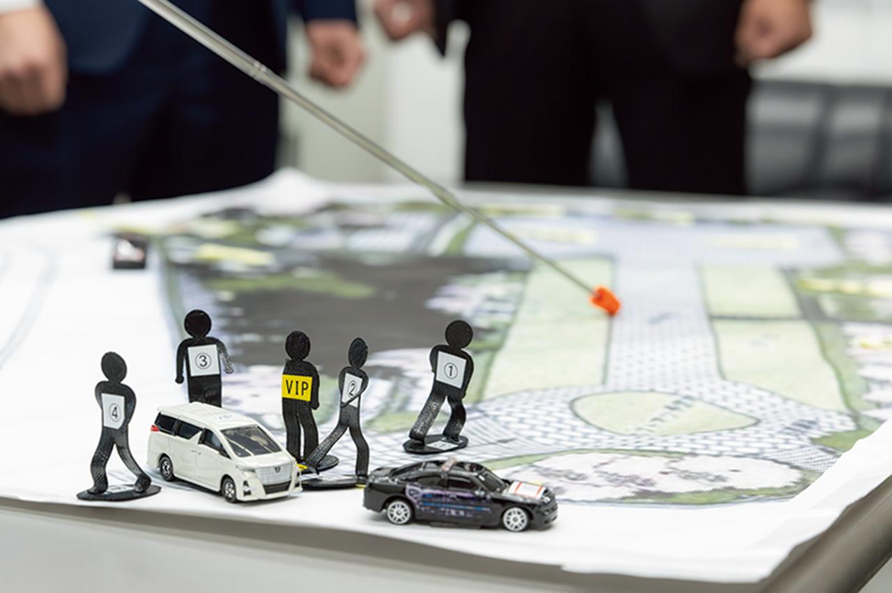画像: 要人警護のための事前のミーティングでは、警護を実施する場所の地図と関係者のミニチュアを基に、任務を遂行する上で必要なチーム内の意思疎通と認識の統一が図られる