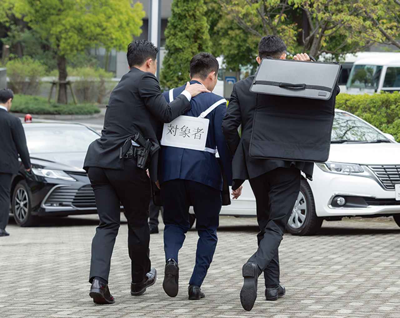 画像: 残りの2人の警務官が要人を脅威者から引き離し、万が一の危険に備え、盾でカバーしながら車両など近くの安全な場所まで誘導する