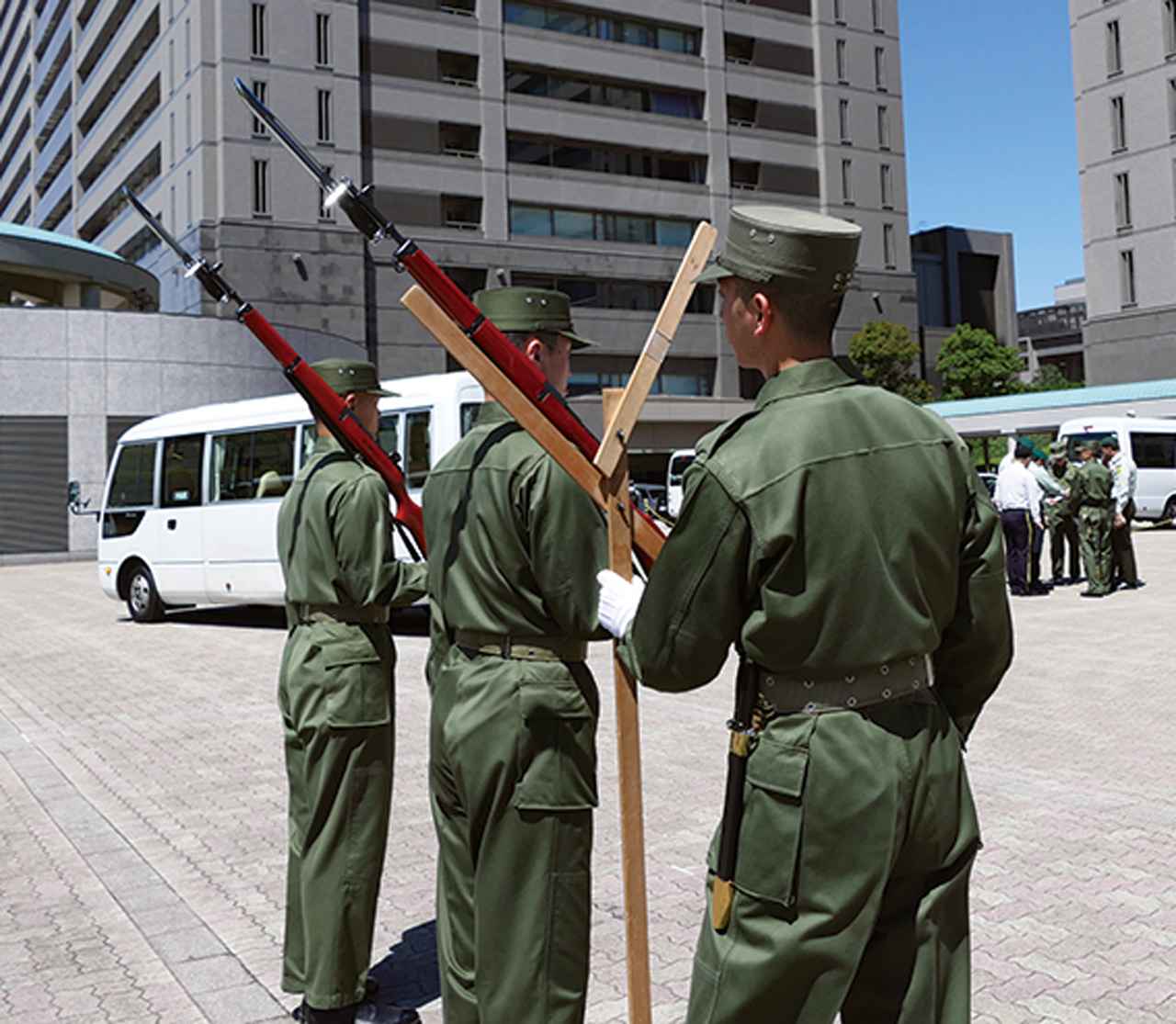 画像: 肩に担いだ儀じょう銃の角度が正しいかどうかを矯正具で確認する
