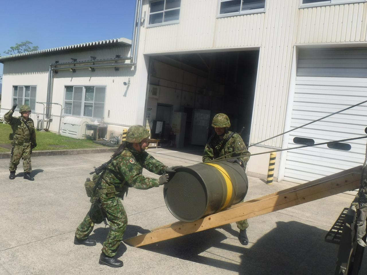 画像: ドラム缶に入った燃料を輸送トラックに積み込む予備自