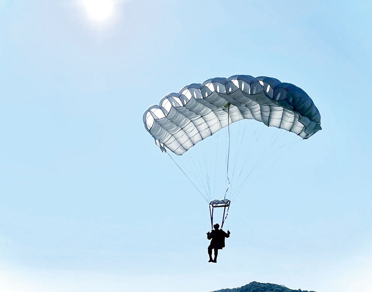 画像: 落下傘を身に着け航空機から降下する訓練。要救助者の下へピンポイント降下できるよう訓練を重ねる