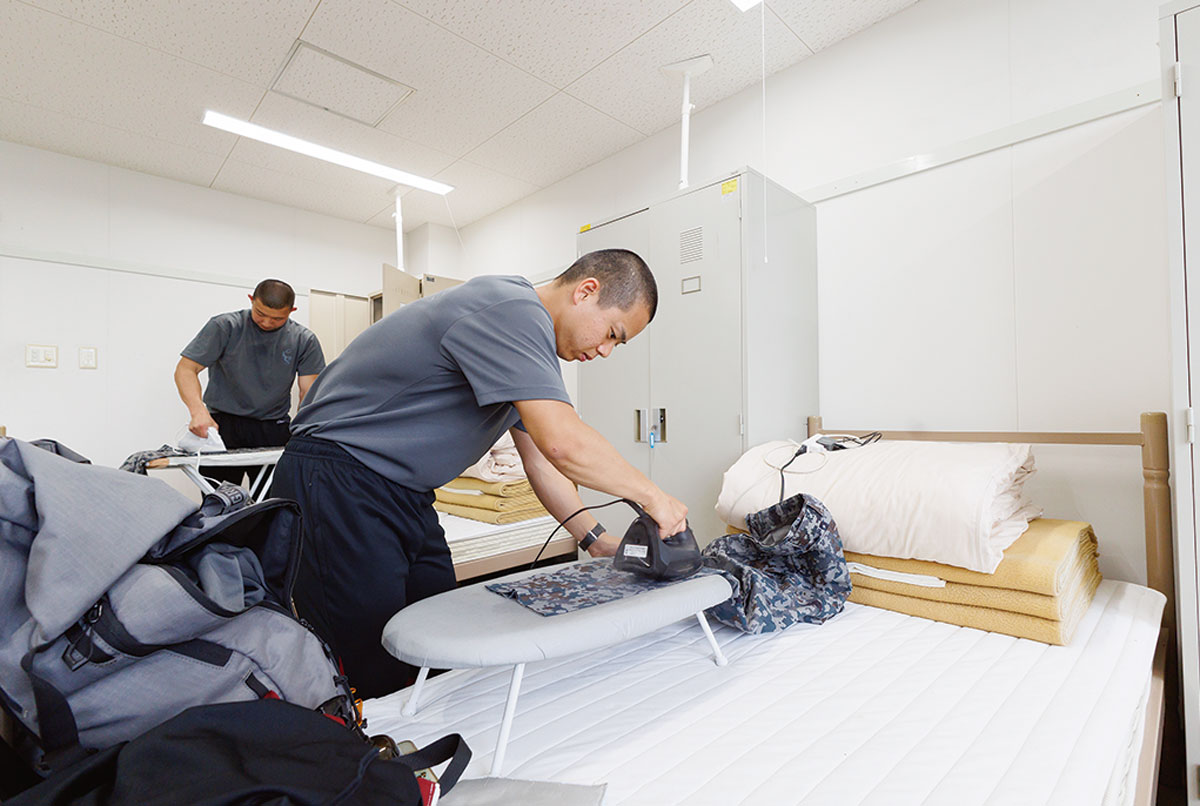 画像: 自由時間に洗濯やアイロンがけをする学生。このときに仲間たちととりとめのない話をするのが息抜きになる