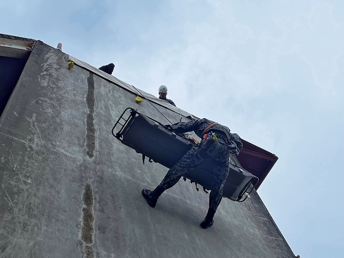 画像: 高さ約11メートルの訓練塔での山岳救助訓練。要救助者を担架に乗せロープで降下。体力を消耗する訓練だ