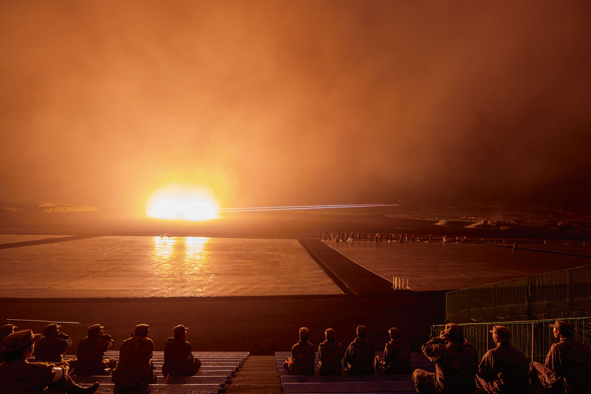 画像: 暗闇の中、主砲を射撃する16式機動戦闘車など。発砲炎で一瞬だけ周囲が昼間のように明るく照らされる