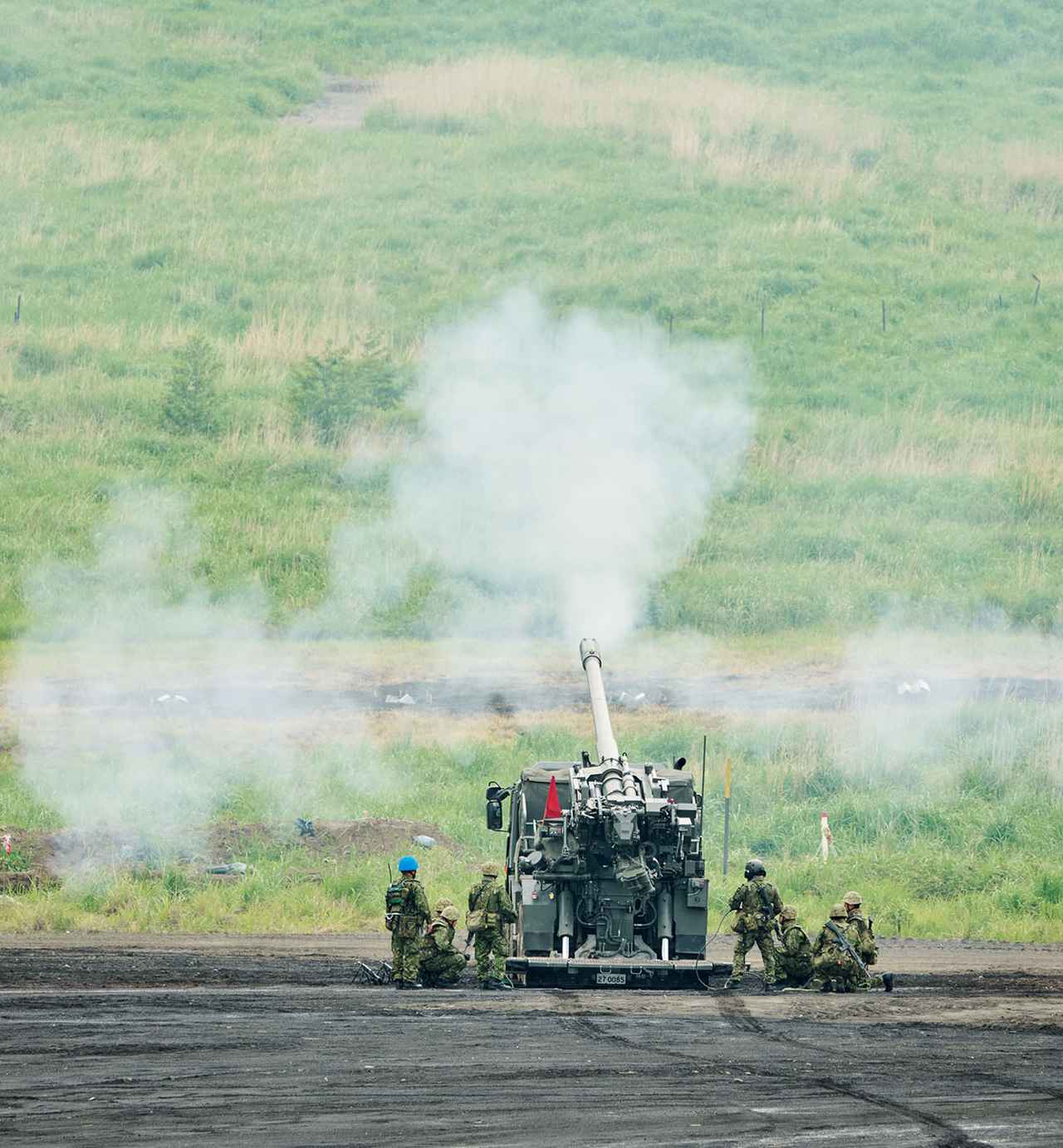 画像: 射撃を行う19式装輪自走155ミリりゅう弾砲。従来のFH70りゅう弾砲と比べて素早く射撃準備、撤収ができることを紹介していた