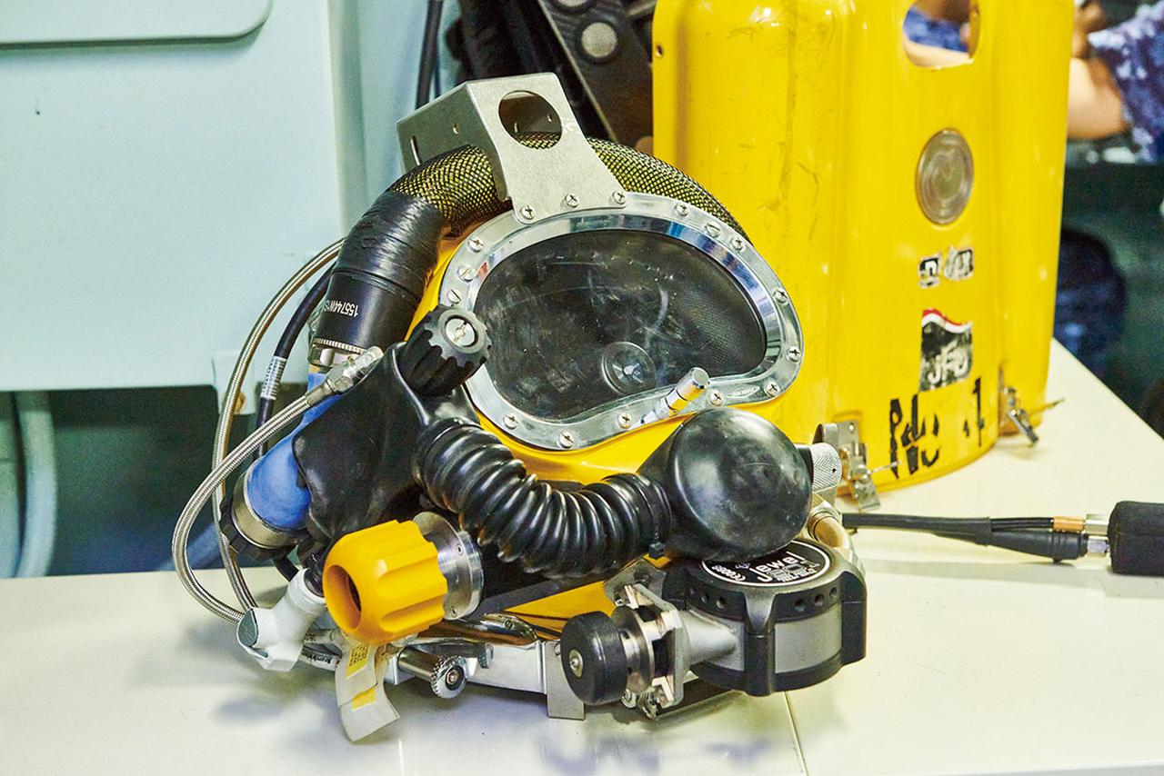 画像: 飽和潜水用のヘルメットは、これだけで20キログラムあるという。このほかにも器材を背負うので、強じんな体力が必要不可欠だ